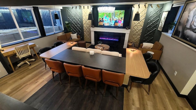 dining space with a glass covered fireplace, wood finished floors, and baseboards