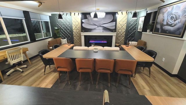 dining area with a glass covered fireplace, baseboards, and wood finished floors