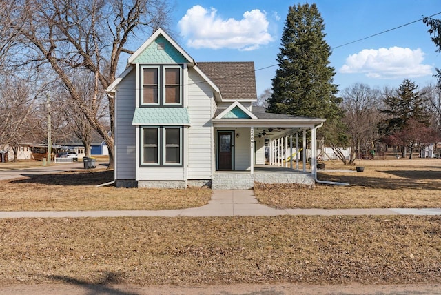 victorian-style house featuring roof with shingles and covered porch