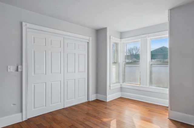 unfurnished bedroom with wood finished floors, baseboards, and a closet