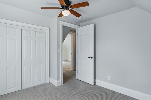 unfurnished bedroom featuring lofted ceiling, light colored carpet, baseboards, and a closet