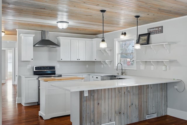 kitchen featuring a sink, wall chimney range hood, a peninsula, white cabinetry, and open shelves