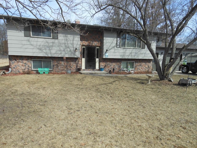 raised ranch featuring a chimney and a front yard