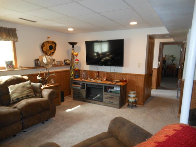 living room with a drop ceiling, carpet, wood walls, and wainscoting