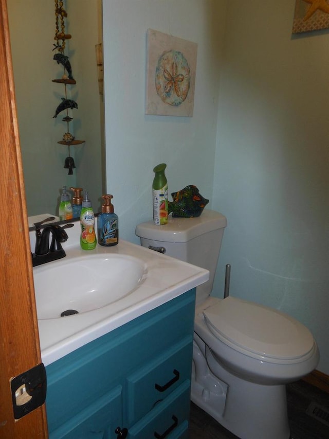 half bathroom featuring vanity, toilet, and visible vents