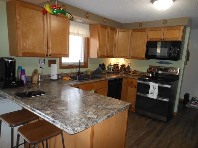 kitchen with black appliances, a breakfast bar, a sink, a peninsula, and dark wood-style flooring