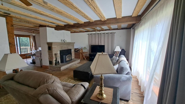 living room featuring a stone fireplace, beamed ceiling, and a ceiling fan