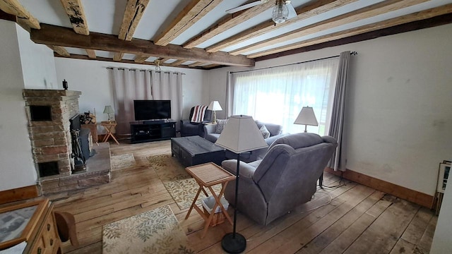 living room with beam ceiling, light wood-style flooring, and baseboards