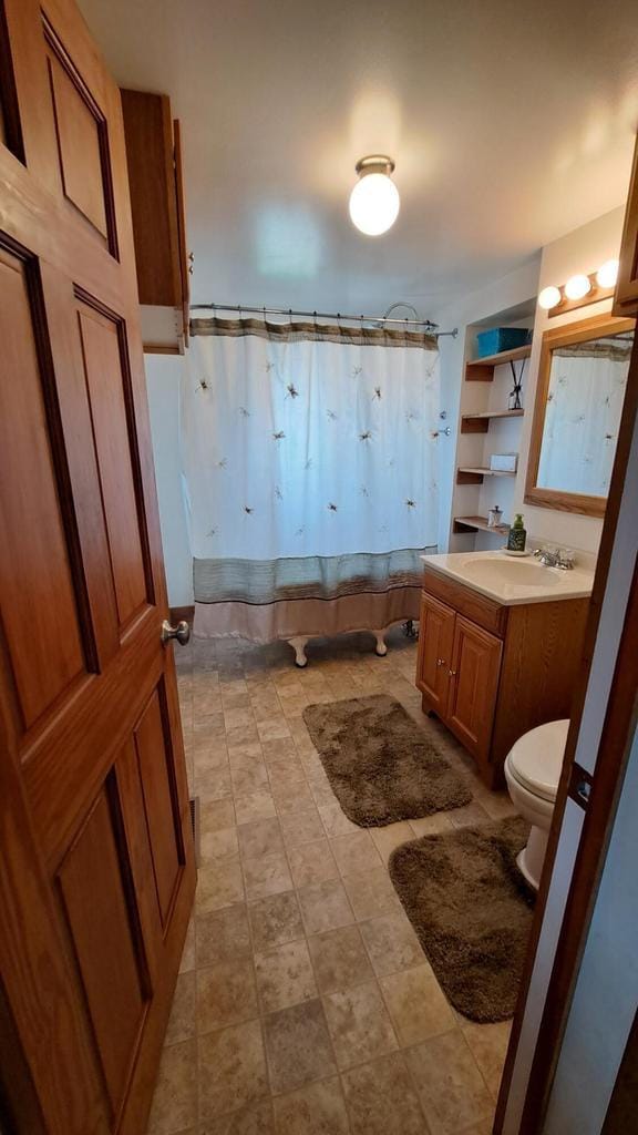 bathroom with curtained shower, toilet, and vanity