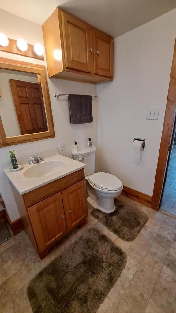 bathroom featuring toilet, vanity, and baseboards