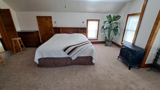 bedroom with baseboards, carpet floors, lofted ceiling, and a wood stove