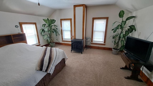 carpeted bedroom featuring multiple windows, a wood stove, and lofted ceiling