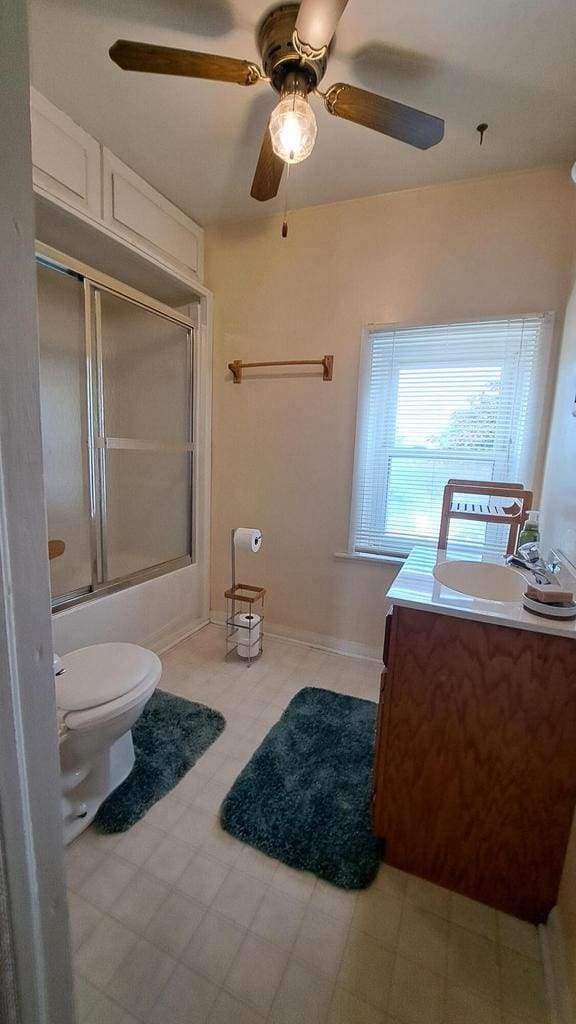 full bath with tile patterned floors, toilet, a ceiling fan, shower / bath combination with glass door, and vanity