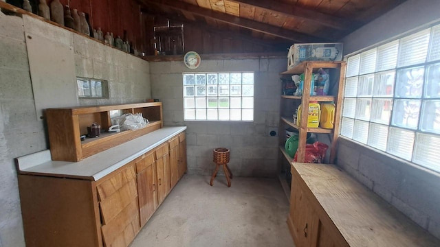 kitchen featuring wood ceiling, light countertops, concrete flooring, vaulted ceiling, and brown cabinetry