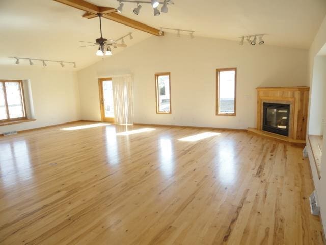 unfurnished living room with lofted ceiling with beams, light wood-style flooring, and a wealth of natural light