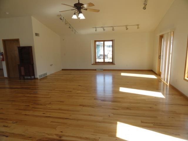 unfurnished living room with visible vents, wood finished floors, a ceiling fan, and vaulted ceiling