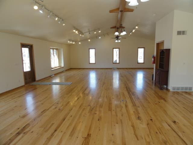 unfurnished living room featuring visible vents, a ceiling fan, lofted ceiling with beams, and light wood-style floors