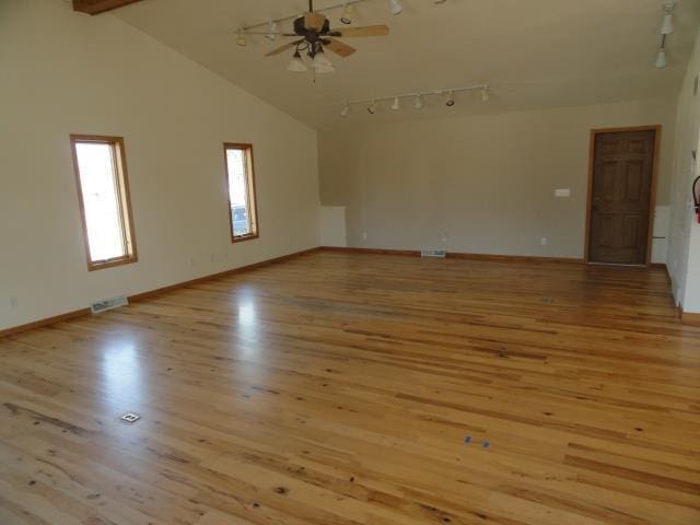 empty room featuring light wood finished floors, track lighting, high vaulted ceiling, and a ceiling fan