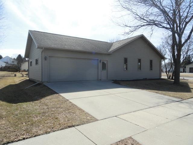 single story home with an attached garage, a shingled roof, and driveway