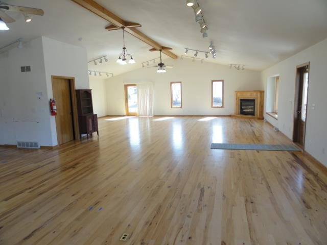 unfurnished living room featuring visible vents, a fireplace with raised hearth, ceiling fan, and wood finished floors