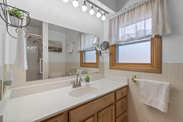 bathroom featuring a wainscoted wall, toilet, tile walls, a shower, and vanity