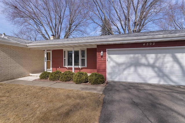 ranch-style house with a chimney, driveway, and an attached garage