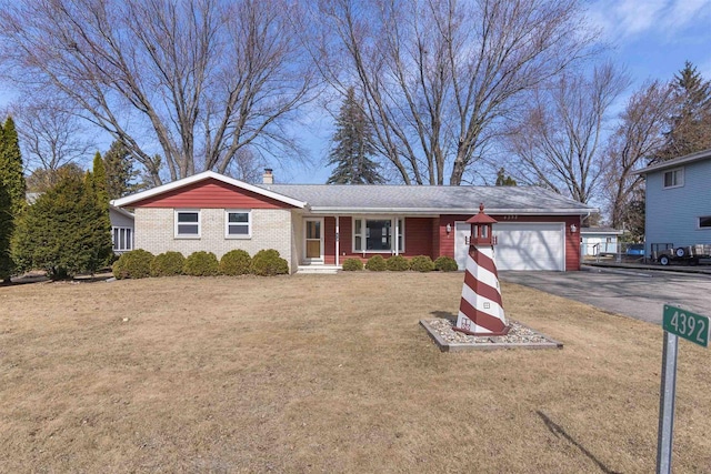 ranch-style home with a front yard, an attached garage, a chimney, aphalt driveway, and brick siding