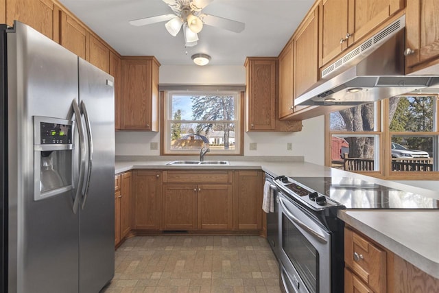 kitchen with under cabinet range hood, stainless steel appliances, brown cabinetry, and a sink