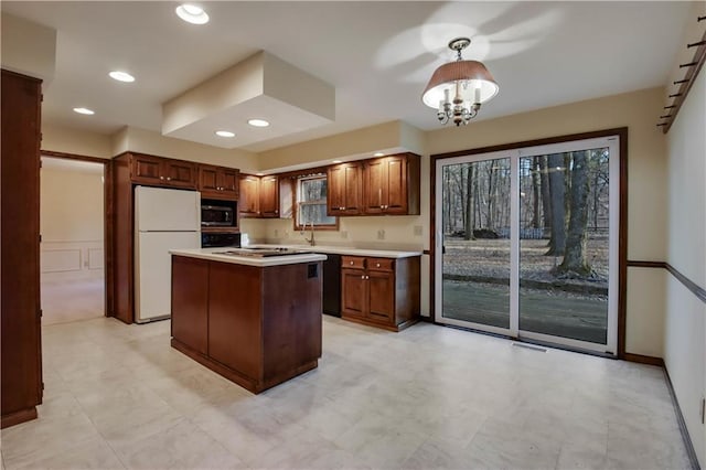 kitchen featuring a kitchen island, oven, built in microwave, light countertops, and freestanding refrigerator