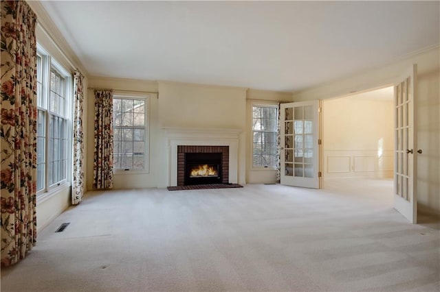 unfurnished living room with visible vents, a fireplace, french doors, a decorative wall, and carpet flooring