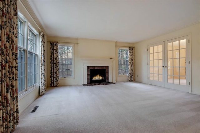 carpeted living room featuring visible vents, crown molding, a fireplace, and french doors