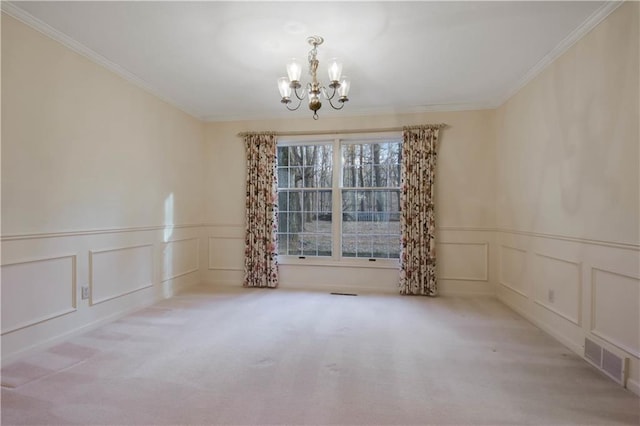 spare room with visible vents, ornamental molding, a decorative wall, carpet flooring, and a chandelier