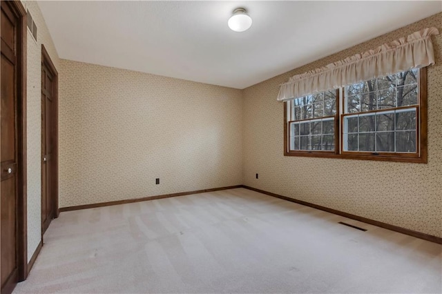 unfurnished bedroom with visible vents, light carpet, and wallpapered walls