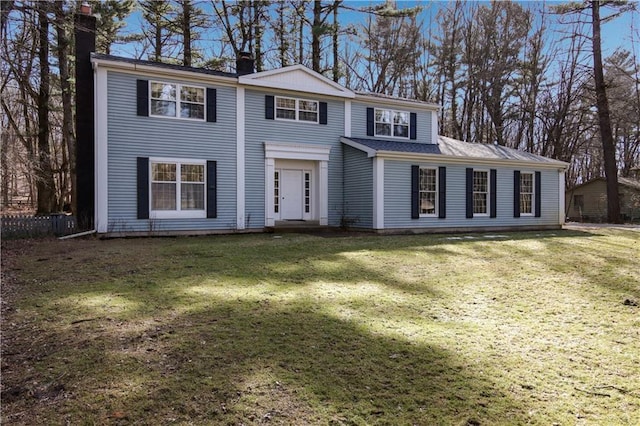 colonial inspired home with a chimney and a front lawn