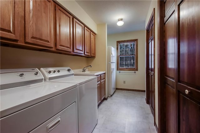 washroom with cabinet space, independent washer and dryer, baseboards, and a sink