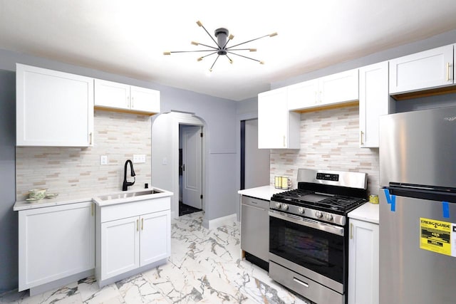 kitchen featuring a sink, stainless steel appliances, marble finish floor, and white cabinets