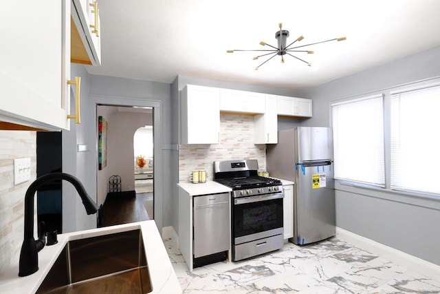 kitchen with marble finish floor, a sink, white cabinetry, stainless steel appliances, and a chandelier