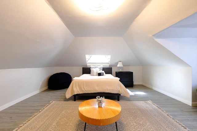 bedroom with baseboards, wood finished floors, and vaulted ceiling