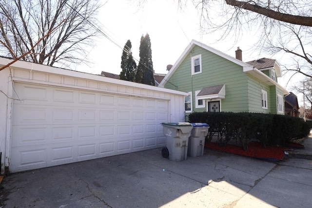 view of property exterior featuring an outbuilding, a detached garage, and a chimney