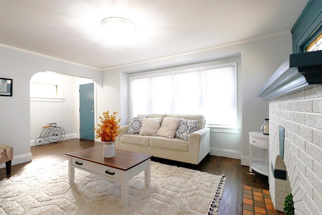 living area featuring arched walkways, ornamental molding, baseboards, and dark wood-style flooring