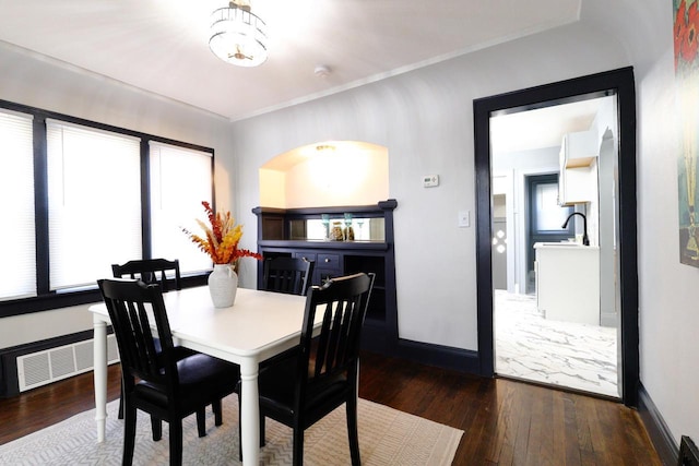 dining room with visible vents, crown molding, baseboards, and wood-type flooring