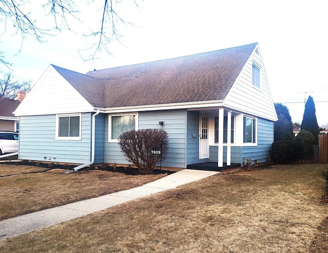 view of front facade with a shingled roof and a front yard