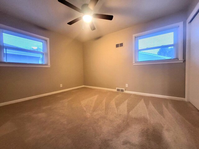 carpeted spare room with visible vents, ceiling fan, and baseboards