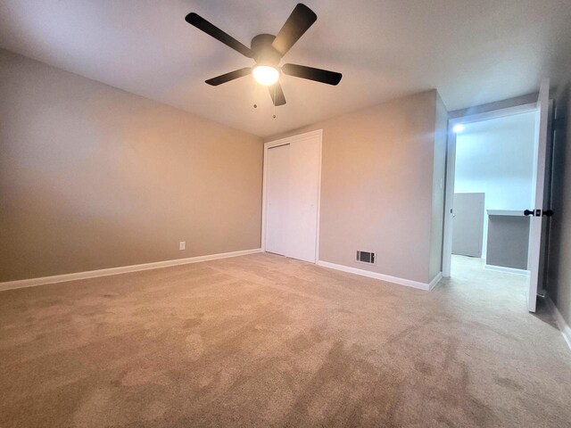 unfurnished room featuring baseboards, a ceiling fan, visible vents, and light carpet