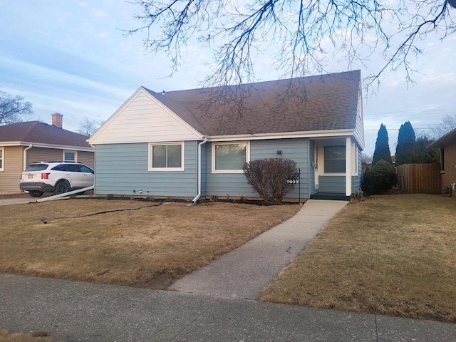 view of front of property featuring a front yard, fence, and roof with shingles