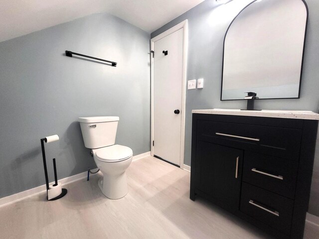 bathroom featuring vanity, toilet, wood finished floors, and baseboards