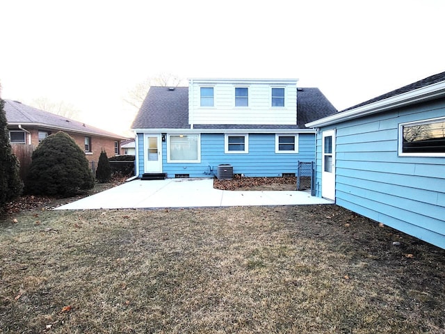 back of house featuring central air condition unit, a lawn, a shingled roof, and a patio