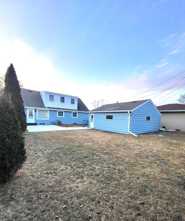 rear view of house featuring a yard, a patio, and roof with shingles