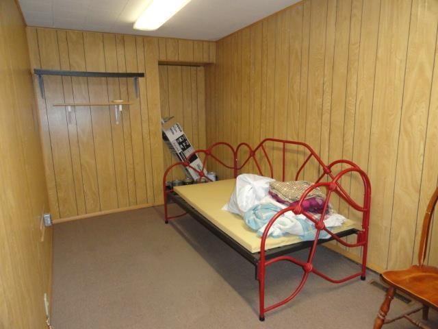 carpeted bedroom featuring wood walls