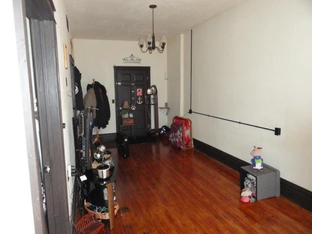 hall with a notable chandelier, baseboards, and wood finished floors